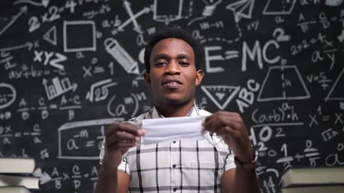 Young Adult Presents Face Mask in Front of Blackboard