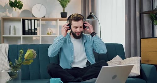 Man Puts on Headphones at Home
