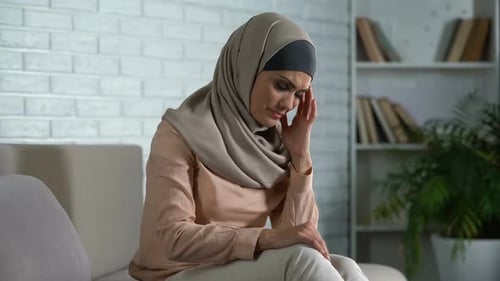 Woman in Hijab with Headache Sitting on Couch