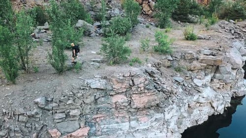 Man Hikes Along Cliffside Rocks Outdoors
