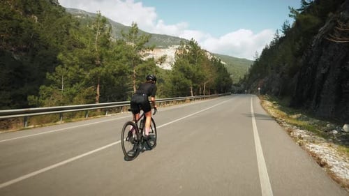 Professional cyclist speeding up on bicycle, pushing pedals out of saddle.