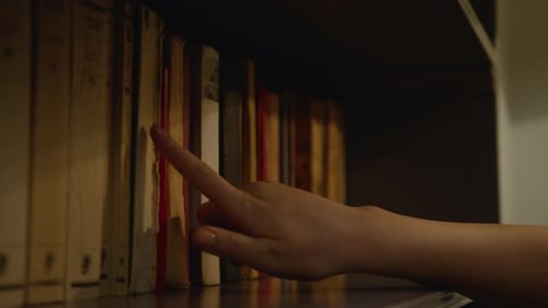 Hand Selects a Classic Book From Bookshelf