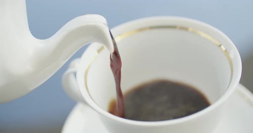 Black Coffee Being Poured Into White Teacup