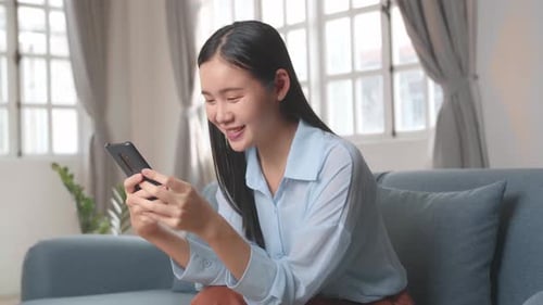 Smiling Woman Using Phone on Comfortable Couch
