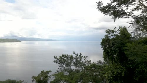 Drone shot flying over trees to reveal a tropical beach in Costa Rica