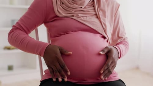 Pregnant Woman Posing Indoors with Hands on Belly