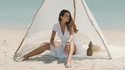 Woman Drinking Coconut Juice While Relaxing on the Beach