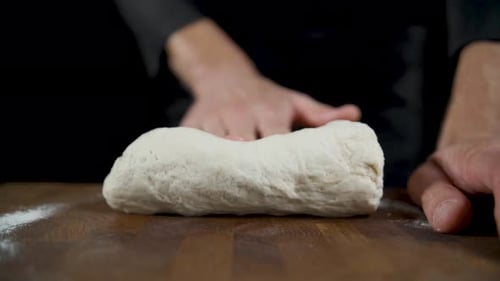Hands Kneading Dough on Wooden Surface