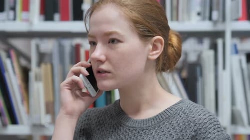 Young Woman Talking on Phone in Library Setting