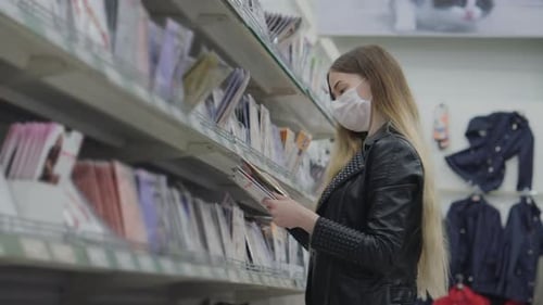 Jovencita con máscara médica comprando medias de nylon en el supermercado