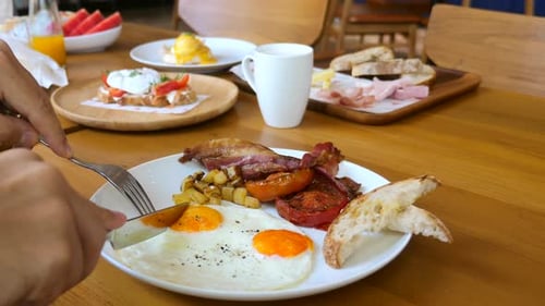 Man Eat Fried Egg with Toasted Bread Bacon and Tomatoes in Cafe Breakfast Food