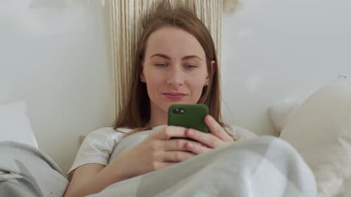 Woman Relaxing in Bed with Mobile Phone