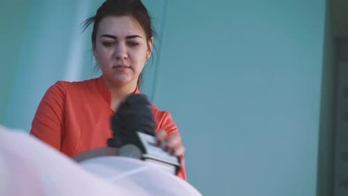 Cosmetologist in Uniform Does Roller Massage of Girl Hip