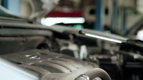 Mechaniker inspiziert Motor mit einer Taschenlampe