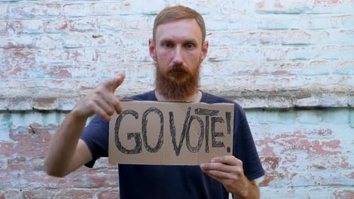 Man shows cardboard with Go Vote sign on brick wall urban background Voting concept Use your voice