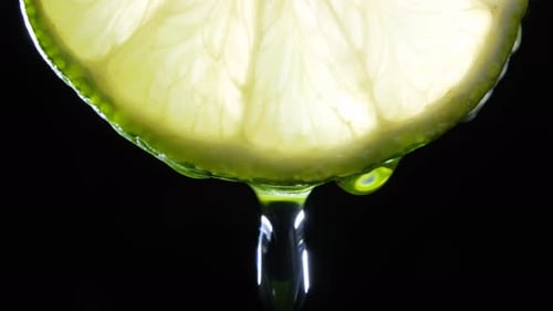 Fresh Slice Lime, a Drop of Water Falls. Black Background