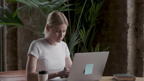 Woman Works on Laptop in Trendy Cafe