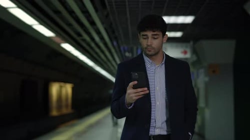 Man in Suit Using Smartphone While Waiting for Subway
