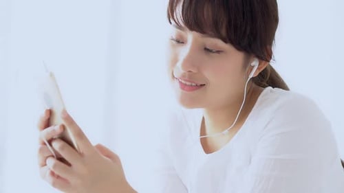 Woman Uses Smartphone Device While Wearing Earbuds