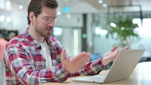 Frustrated Man Typing on Laptop in Office