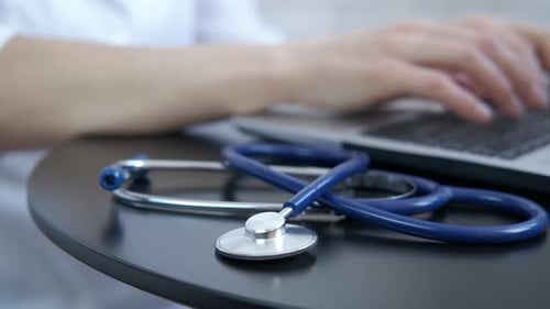 The doctor works on a laptop.