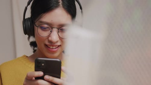 Woman With Headphones Using Cell Phone Indoors