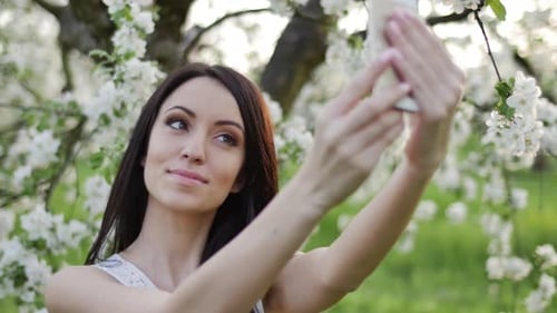 Woman Takes Selfie in Blooming Spring Orchard