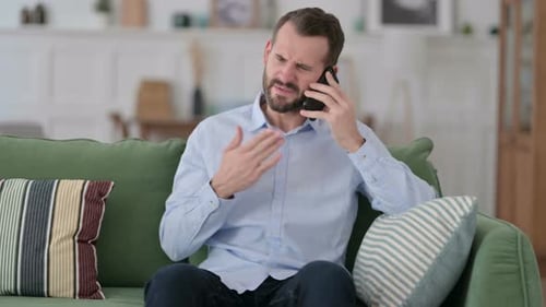 Bearded Man Arguing on Smartphone While Sitting