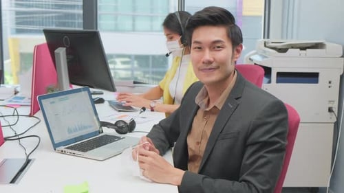 Asian business man removing face mask and look at camera while working in office due to Covid-19.