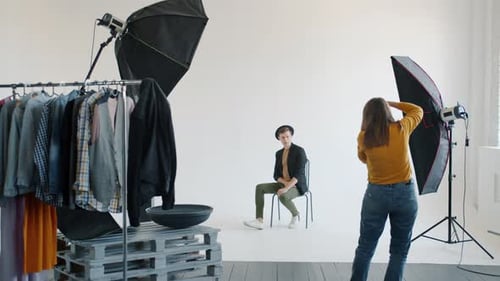 Slow Motion of Female Photographer Taking Pictures of Male Model in Studio