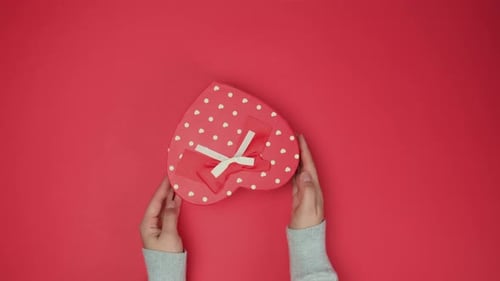 Hands Placing Heart Shaped Gift Box Overhead