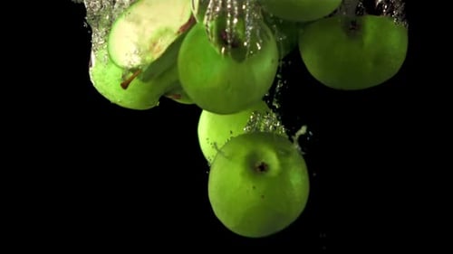 In Superzeitlupe fallen frische Apfelstapel mit Luftblasen unter Wasser