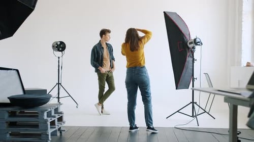 Female Photographer Showing Body Positions To Male Model Working in Studio