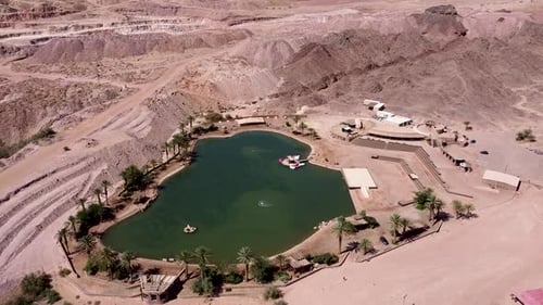 Aerial high angle forward drone shot of an artificial oasis in the middle of the desert, surrounded