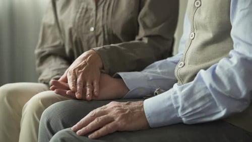 Elderly Couple Sitting on Sofa, Woman Giving Hand to Man, Support, Understanding