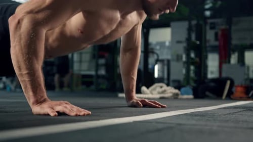 Young male athlete trains in the gym, push-ups from the floor, crossfit, endurance training