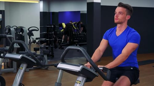 Ein junger fitter Mann trainiert auf einem Heimtrainer in einem Fitnessstudio