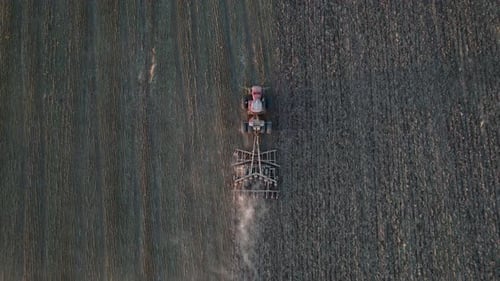 Luftaufnahme von oben auf landwirtschaftlichen Maschinen, die auf kultiviertem Feld arbeiten