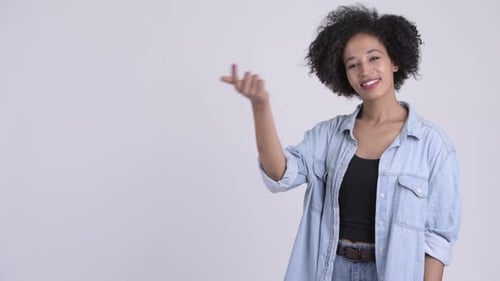 Glückliche junge schöne Afrikanerin schnappt Finger und zeigt etwas