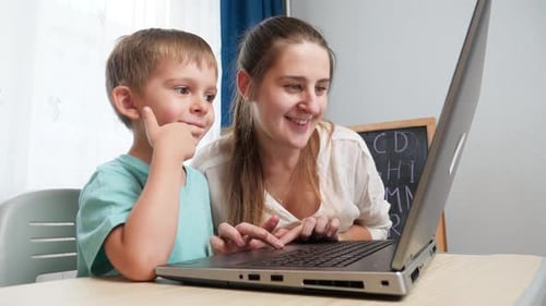 Child and Woman Use Laptop Together Indoors