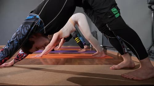 People in Tracksuits Stand in Yoga DownwardFacing Dog Pose