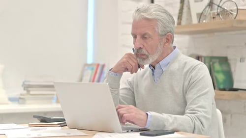 Mature Man Working at Laptop in Bright Office