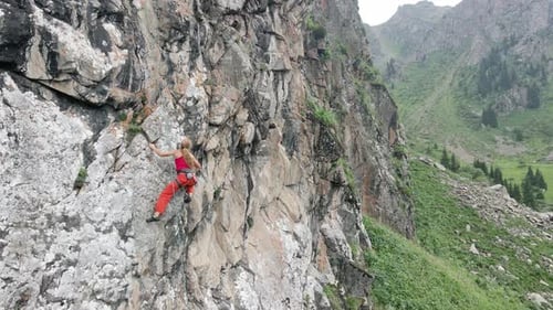 Woman Athlette Climbing on the High Rock in the Mountains