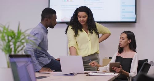 Happy diverse group of business people working together, using laptop in modern office