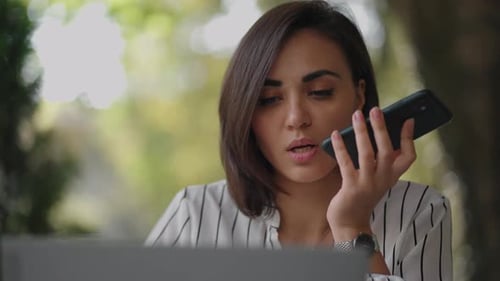Woman Talking on Cell Phone Using Laptop