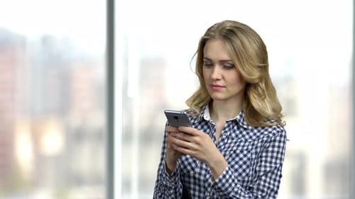 Woman Using Smartphone in Bright Indoor Setting