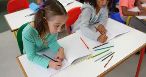 High angle view of mixed-race schoolkids drawing on notebook in the classroom 4k