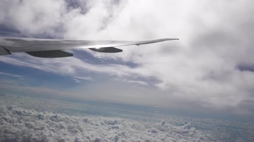 Aircraft Wing Between Layers of White Clouds High in the Sky at Sunny Weather