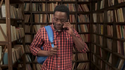 Male African American Student Talking on the Phone and Smiling in the Library