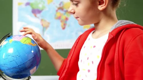 Schulmädchen schaut sich den Globus im Klassenzimmer der Schule an